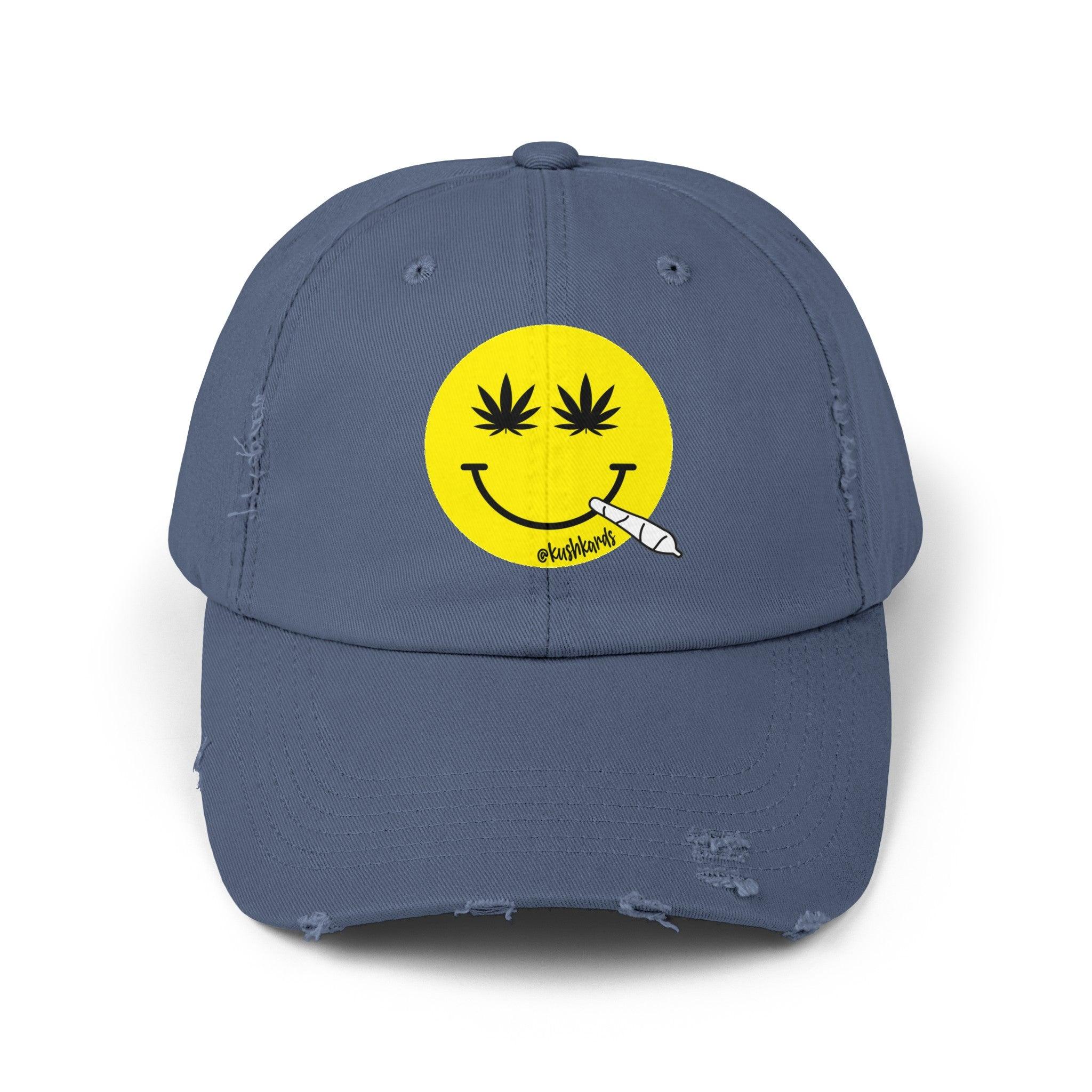 Nice Jay Smiley Face Distressed Dad Hat featuring a playful yellow smiley face with cannabis leaves for eyes and a rolled joint in the mouth, on a scotland blue colored cotton twill cap.