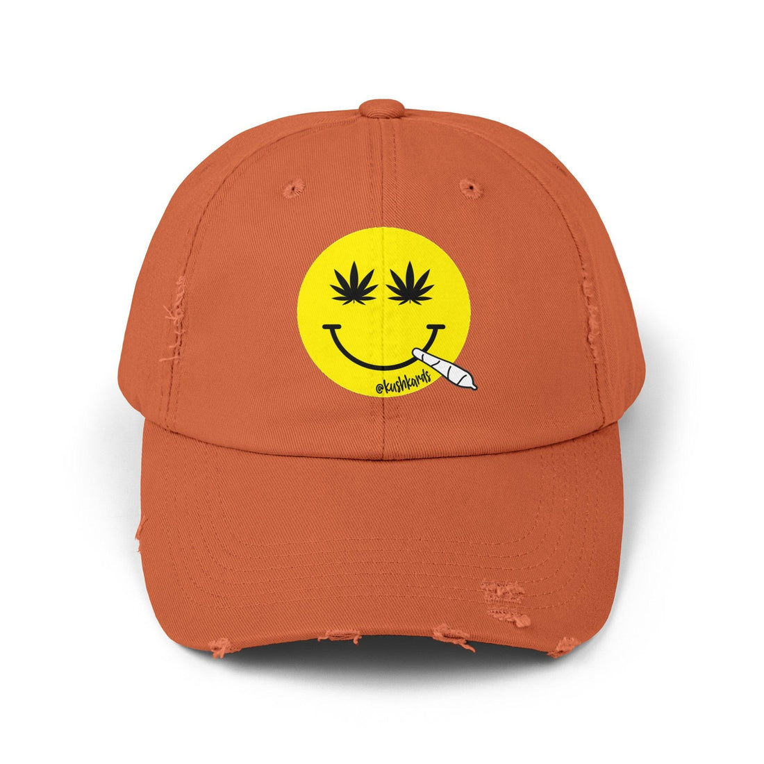 Nice Jay Smiley Face Distressed Dad Hat featuring a playful yellow smiley face with cannabis leaves for eyes and a rolled joint in the mouth, on a burnt orange cotton twill cap.