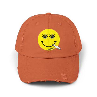 Nice Jay Smiley Face Distressed Dad Hat featuring a playful yellow smiley face with cannabis leaves for eyes and a rolled joint in the mouth, on a burnt orange cotton twill cap.