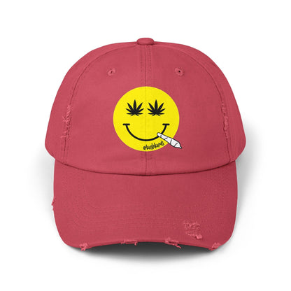 Nice Jay Smiley Face Distressed Dad Hat featuring a playful yellow smiley face with cannabis leaves for eyes and a rolled joint in the mouth, on a dashing red cotton twill cap.