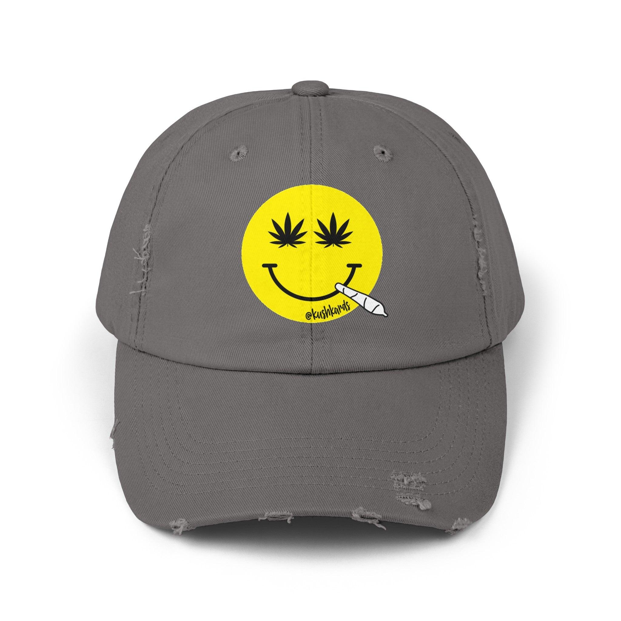 Nice Jay Smiley Face Distressed Dad Hat featuring a playful yellow smiley face with cannabis leaves for eyes and a rolled joint in the mouth, on a nickel colored cotton twill cap.