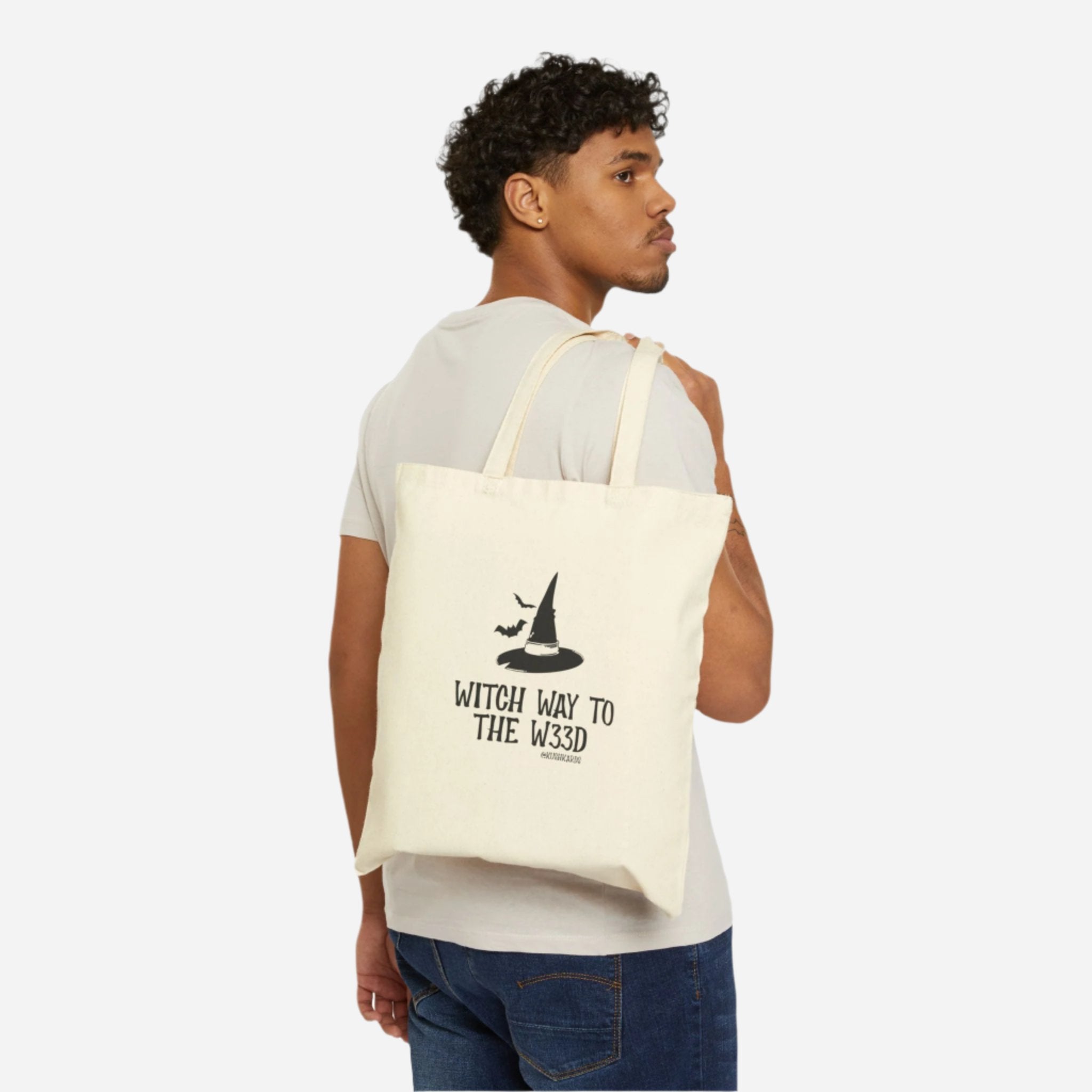 Front of the Witchy Tree Cotton Canvas Tote Bag featuring a black witch hat and bats with the phrase &quot;Witch Way to the W33D.&quot;