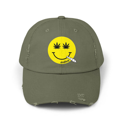 Nice Jay Smiley Face Distressed Dad Hat featuring a playful yellow smiley face with cannabis leaves for eyes and a rolled joint in the mouth, on a light olive cotton twill cap.