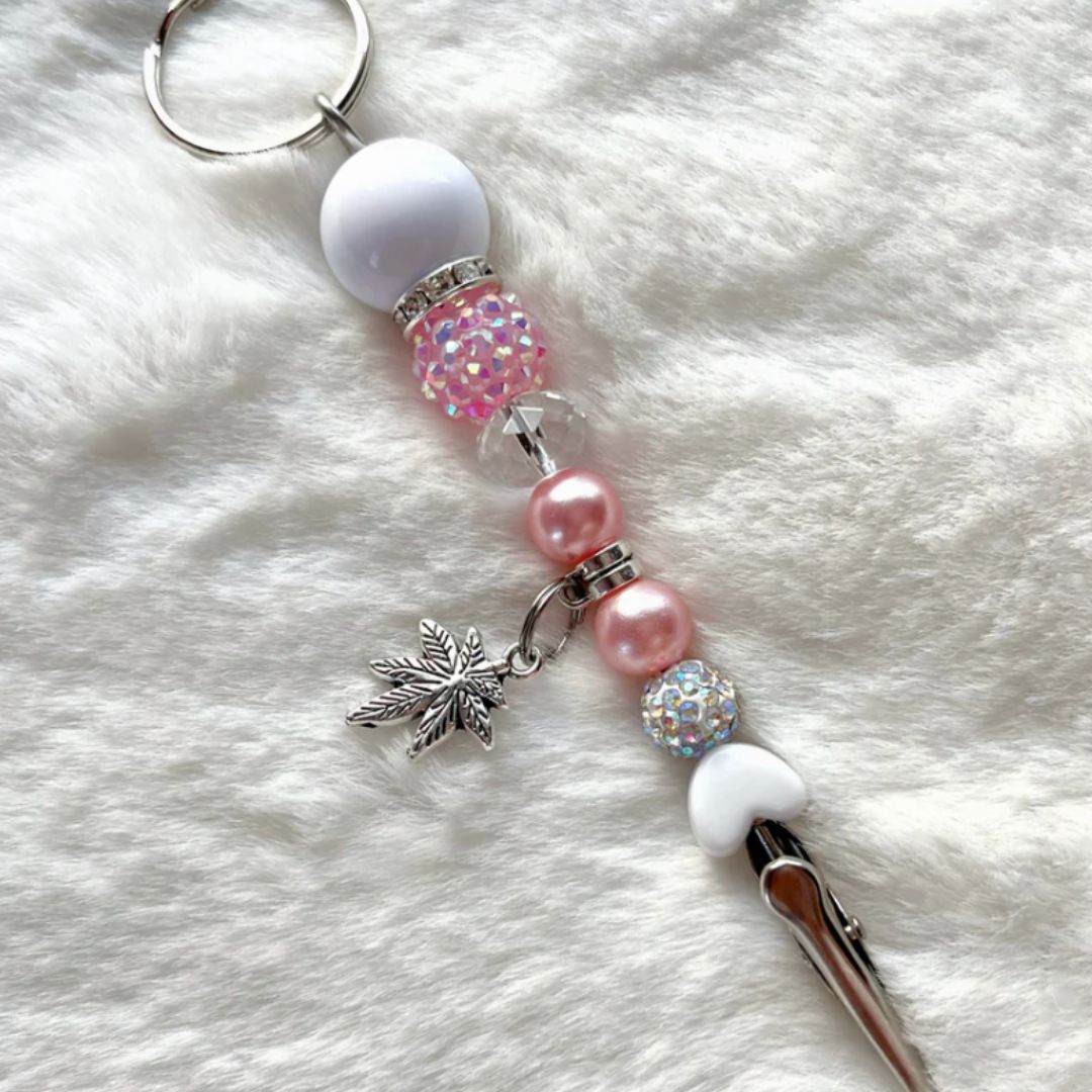 pink and white beaded roach clip with rhinestones and a silver cannabis leaf charm, handmade by Trap Mami LA.