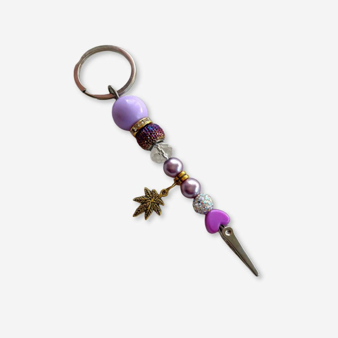 purple and gold beaded roach clip with rhinestones and a gold cannabis leaf charm, handmade by Trap Mami LA.