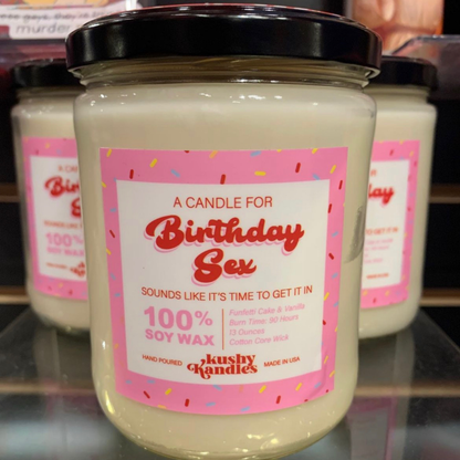 A close-up of the &quot;Birthday Sex&quot; soy wax candle with funfetti cake and vanilla scent, surrounded by more candles on a display shelf, evoking a playful and sweet atmosphere.