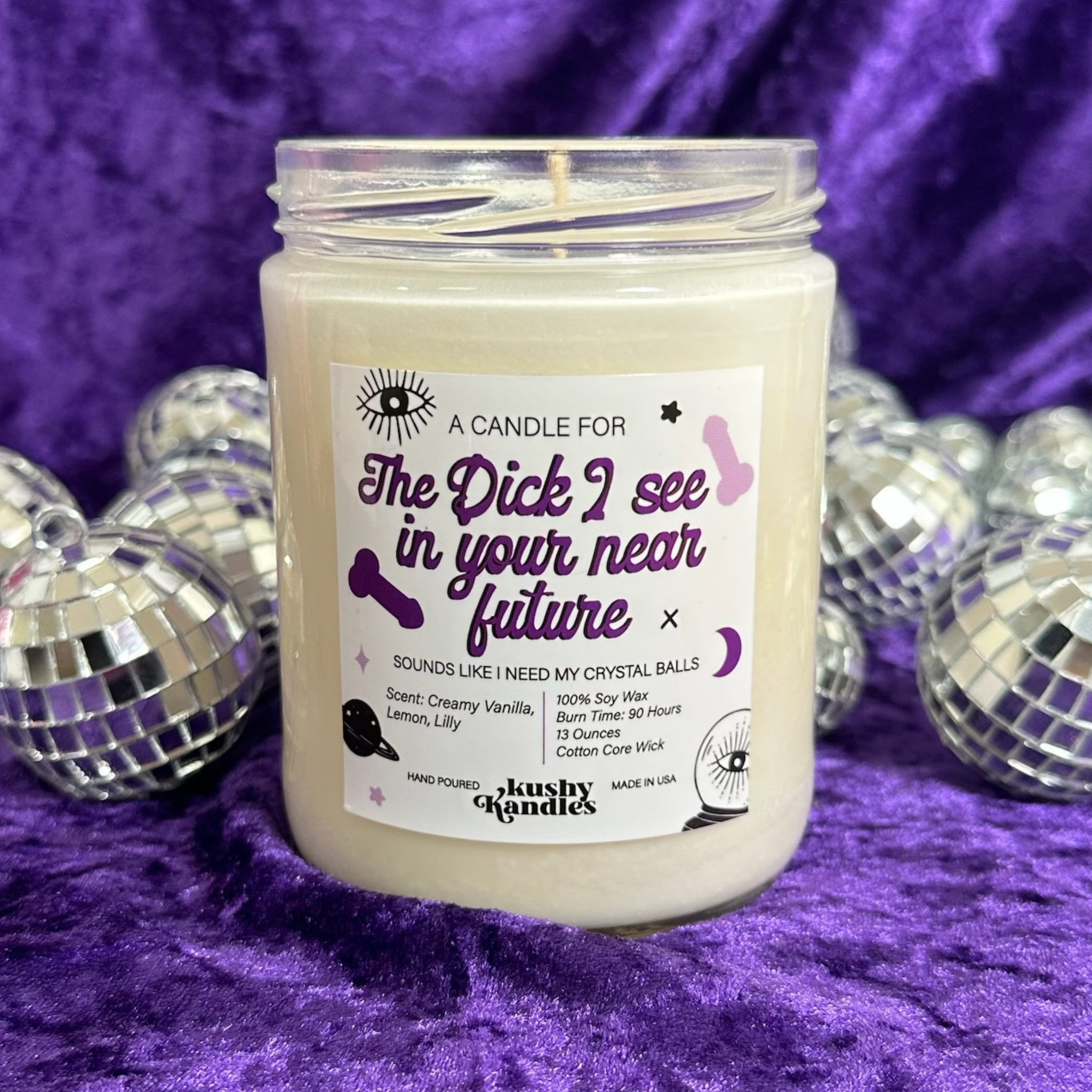 A Future Dick Vanilla &amp; Lemon Soy Wax Candle with creamy vanilla and lemon scent, displayed on a purple velvet background with shiny disco balls, evoking fun and playful vibes.